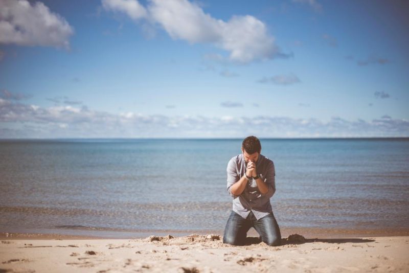 ビーチで祈る男